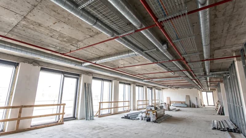 Coordinated ducts, sprinkler pipework and cable tray running below an exposed concrete soffit during fit-out.